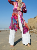 Person wearing a colorful open-front cardigan with front pockets on a beach