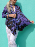 Standing front of a aqua colored wall, a frontal shut is showing one side pulled open to show you the actual asymmetric shape of the front.