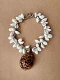 placed flat on cardboard - 48 uncut white cowrie shells with the pendant, a knob-loop closure