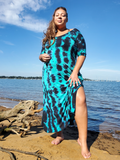 My best seller dress in a size 3XL,  modeled by ana; she has one hand on her upper thigh,  her knee and lower leg is showing in the side slit. the dress also has a deep V-neck, a bit longer than usual short sleeves, and side pockets. Jade-black tie dye.
