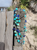 Pretty Blue-Green Gemstones Long Necklace, displayed on a wooden fence