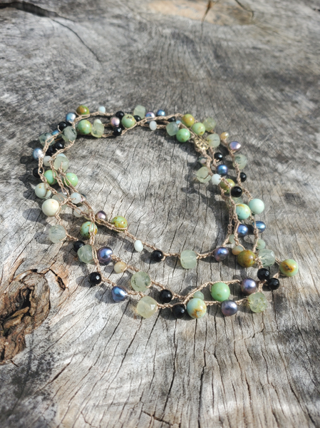 a 52' long crocheted necklace on a nylon cord. the various size and shape gem beads  have a nice earthy green mix; black, peacock pearls and green semiprecious beads