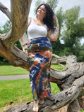 Katie is standing on a dried up tree, looking very pretty in her white tank top and curly long hair..