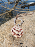 necklace placed on a big rock at the beach, with the Atlantic Ocean in the back