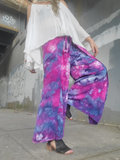 Person wearing colorful ice-dye rayon wrap pants and a white top against a graffiti-covered wall.