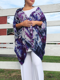 My cocoon shaped sweater poncho modeled by a young woman. She is standing front of a white stable fence, arms across her chest.