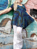 A similar shot; I'm leaning against a graffiti wall. I'm wearing a pair of white distressed bell bottoms with the tunic. The originally teal colored garment was tie dyed over with olive and navy colors, the result is a peacock combination