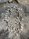 sliced Cowrie shells strung up on a greyish hemp cord, then crocheted into a 52" long layering necklace. The shells are about an incs apart with the hemp cording all around.