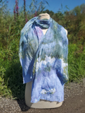 pastel colored textured scarf in green blue wrapped around a form with flowers in the background