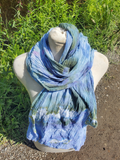 pastel colored textured scarf in green blue wrapped around a form with flowers in the background