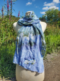 pastel colored textured scarf in green blue wrapped around a form with flowers in the background