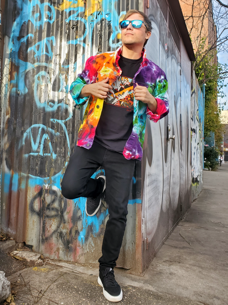 Very colorful denim jacket, modeled by my son Rob, he's leaning against a graffiti wall; jacket open, sleeves rolled. 