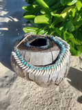 Decorative coconut shell with beads on a sandy background