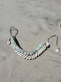 An with shell and amazonite beads on a sandy beach