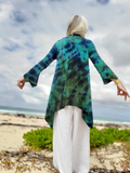 Person wearing a green and blue tie-dye shirt on a beach