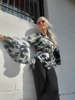 Person wearing a patterned coat standing against a white wall.