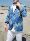 Person wearing a blue patterned jacket and white pants on a sandy beach.