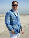 Man wearing a blue ice dye blazer and sunglasses on a beach