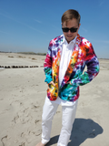 Person wearing a colorful tie-dye jacket on a beach