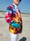Person wearing a colorful tie-dye jacket on a beach