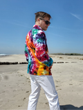 Person wearing a tie-dye shirt and sunglasses on a beach