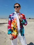 Person wearing a colorful tie-dye jacket on a beach