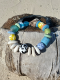 Colorful beaded bracelet on a piece of driftwood with a beach background