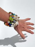 colorful bracelets on a hand against a white wall