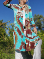 Person wearing a tie-dye jacket with a blue sky and trees in the background
