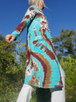 Person wearing a tie-dye dress with a blue and brown pattern outdoors. A side view.