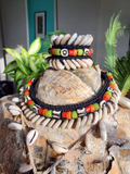 Decorative choker and a matching bracelet with shells and beads on a form, surrounded by plants.