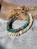 Necklace with turquoise beads and white cowrie shells on a wooden surface