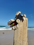 Decorative shell bracelet on a wooden post with a beach and ocean background