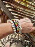 Hand wearing a beaded bracelet with a natural background