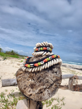 Decorative shell and bead necklace on a wooden post with a beach and ocean background