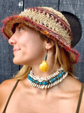 chunky shells beaded choker worn with shell earrings and a straw hat
