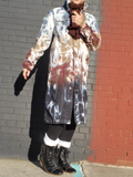 Person wearing a tie-dye coat against a brick wall.