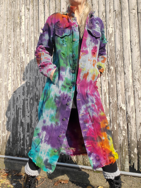 frontal view of the long distressed denim coat: it is hand dyed in bright rainbow colors. The light denim febric holds the colors a bit muted, so they are not as bright as a white garment tie dye in the same colors. 
