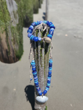 Blue beaded necklace draped over a cactus plant on a street
