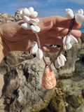 shells worked on a hemp rope, held by a hand front of rocks