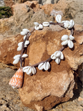 white shell necklace with a big cone shell pendant displayed on the rocks