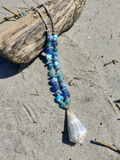 Beaded necklace with a shell pendant on sandy ground