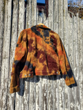 Back shot of tie dye orange and black corduroy jacket  on a wooden fence