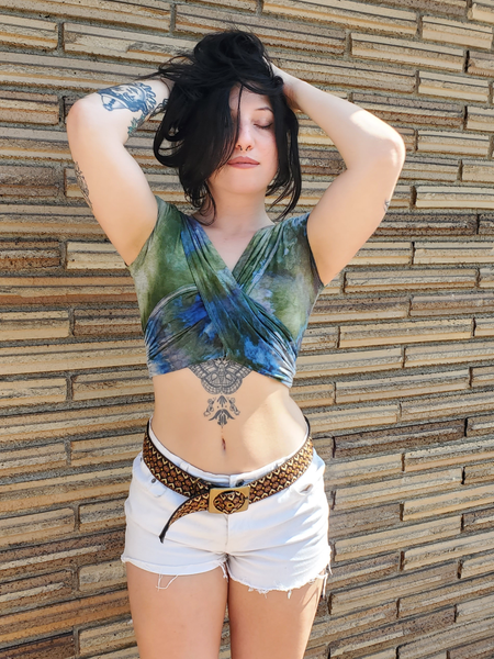 Woman posing against a brick wall wearing a sleeveless top and shorts.