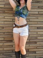 Person wearing an ice dye cross-front top, shorts, and knee-high boots against a brick wall.
