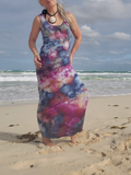 Woman in a tie-dye dress standing on a beach with ocean waves in the background