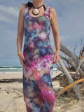 Person wearing a tie-dye dress on a beach with ocean and sky in the background