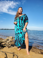 My best seller dress in a size 3XL,  modeled by ana; she has one hand on her upper thigh,  her knee and lower leg is showing in the side slit. the dress also has a deep V-neck, a bit longer than usual short sleeves, and side pockets. Jade-black tie dye.