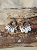 Pair of earrings with shell accents on a wooden surface
