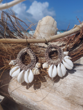Brown crochet earrings with white shells on a beach setting